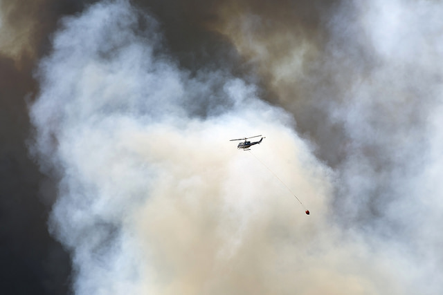 A helicopter carries fire retardant to the wildfire burning in a Fort McMurray neighbourhood on Wednesday, May 4, 2016. (photograph by Chris Schwarz/Government of Alberta)